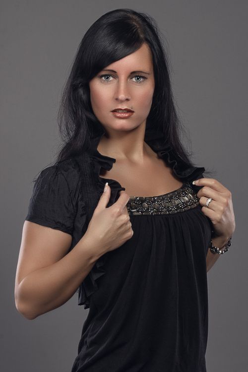 Free Stylish portrait of a woman with long hair in a black top against a gray background. Stock Photo