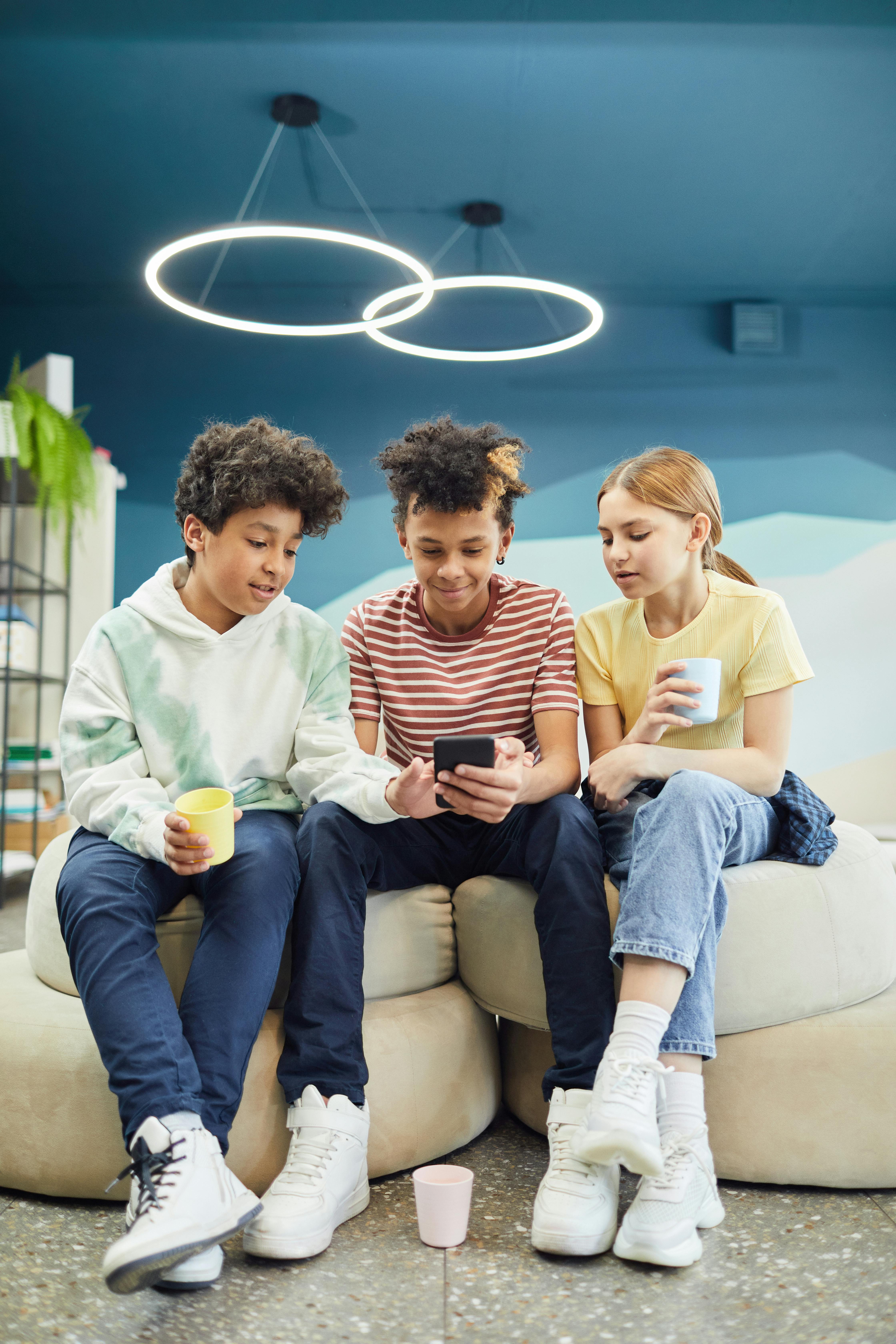 cheerful friends using smartphones together