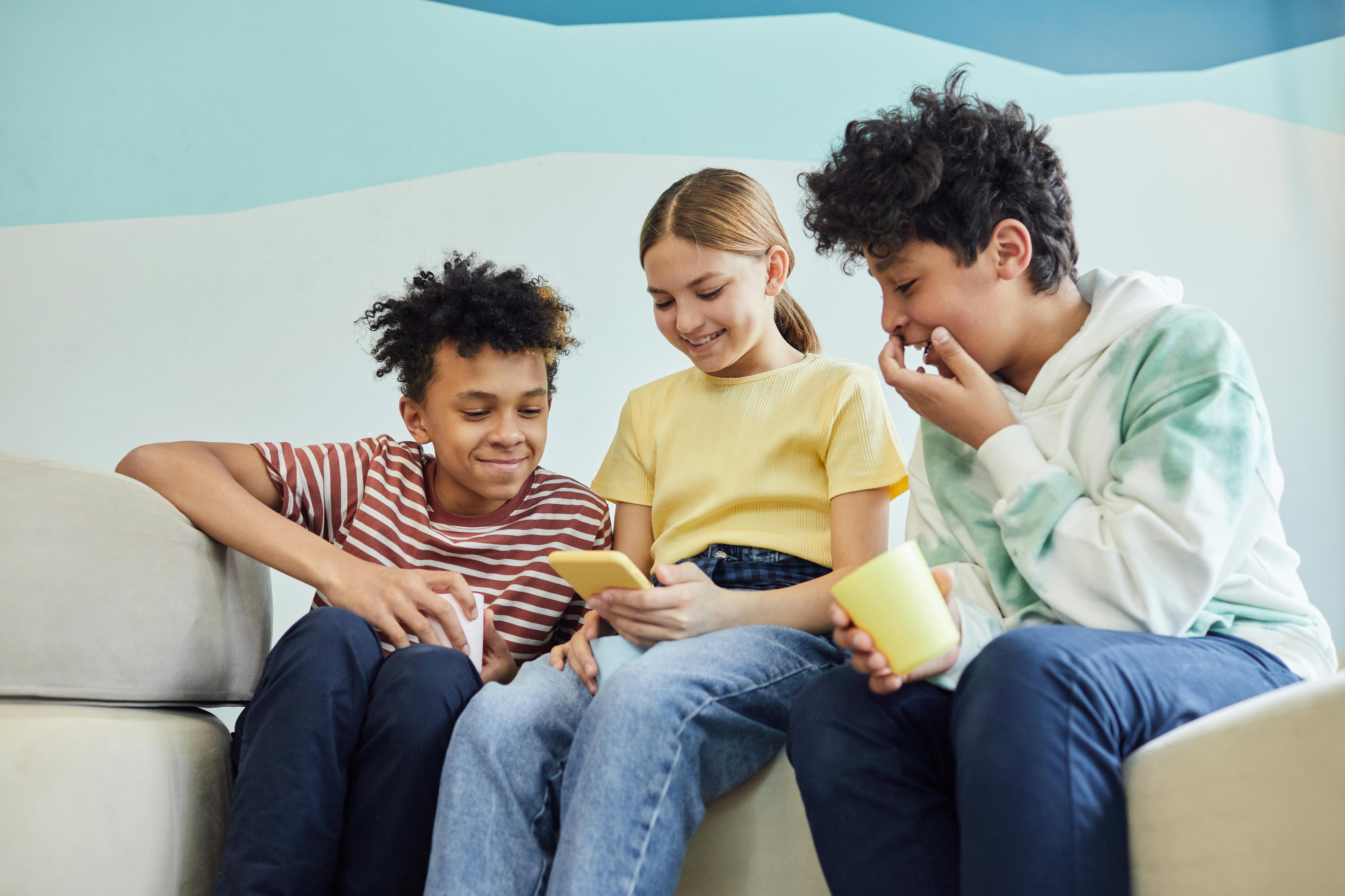 group of cheerful friends using smartphone