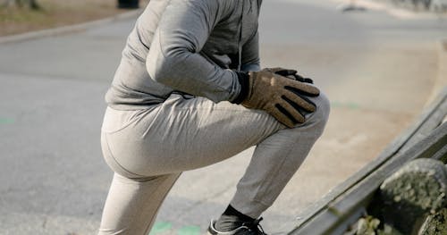 Free Side view of crop anonymous male athlete in sportswear stretching legs before training in city park in daylight Stock Photo