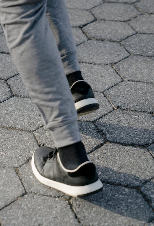 Crop legs of unrecognizable man running on pavement
