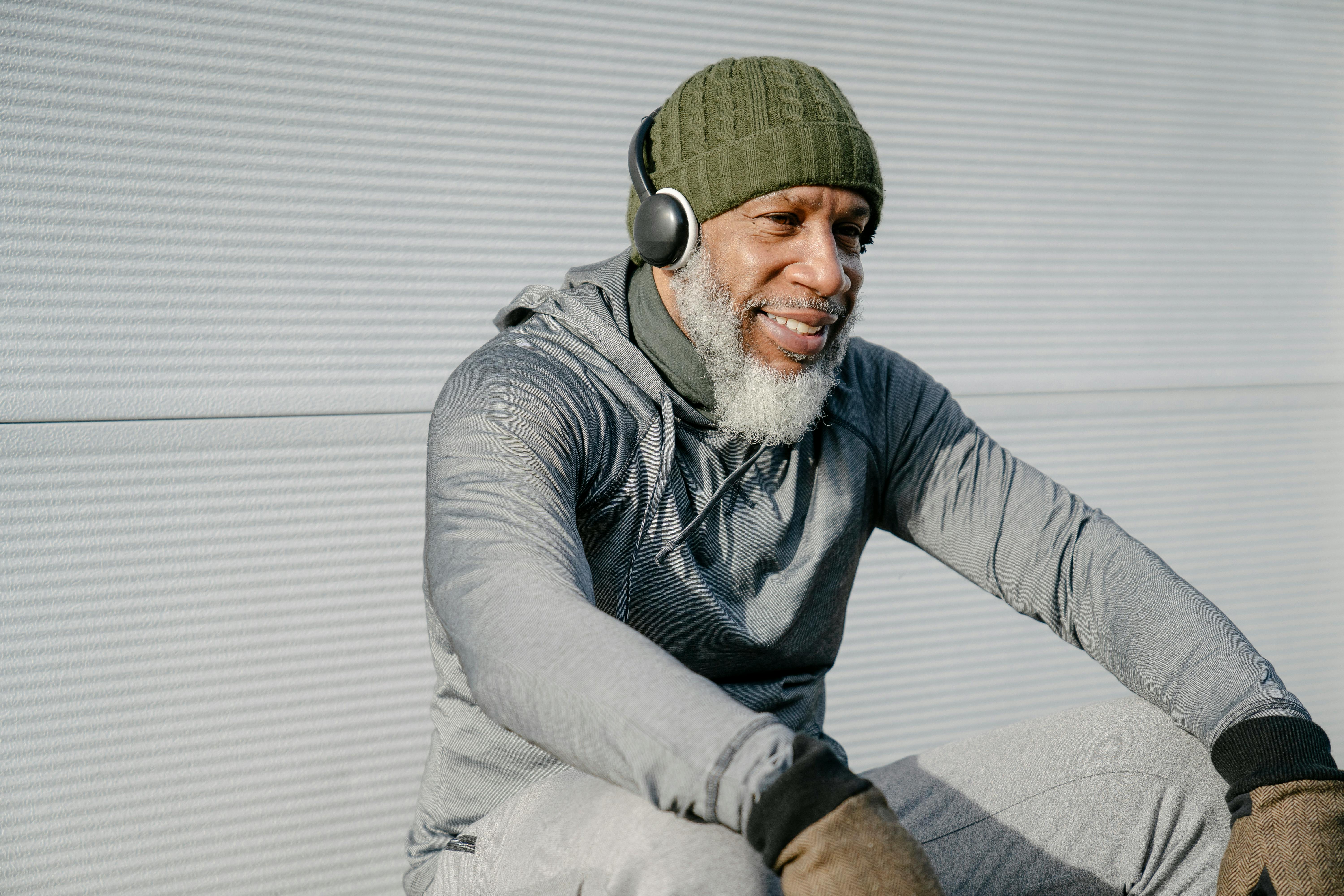 smiling elderly black man in warm clothes sitting with headphones