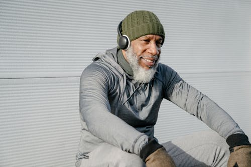 Smiling elderly black man in warm clothes sitting with headphones
