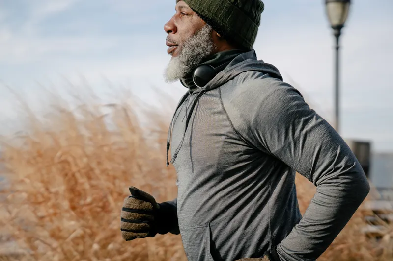 An older man running steadily through winter grass at first light