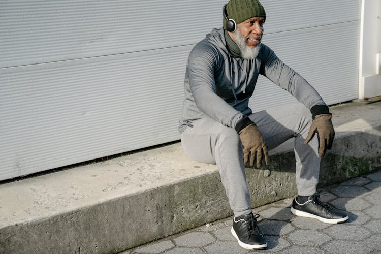 Stylish Mature Black Man Sitting On Street Curb