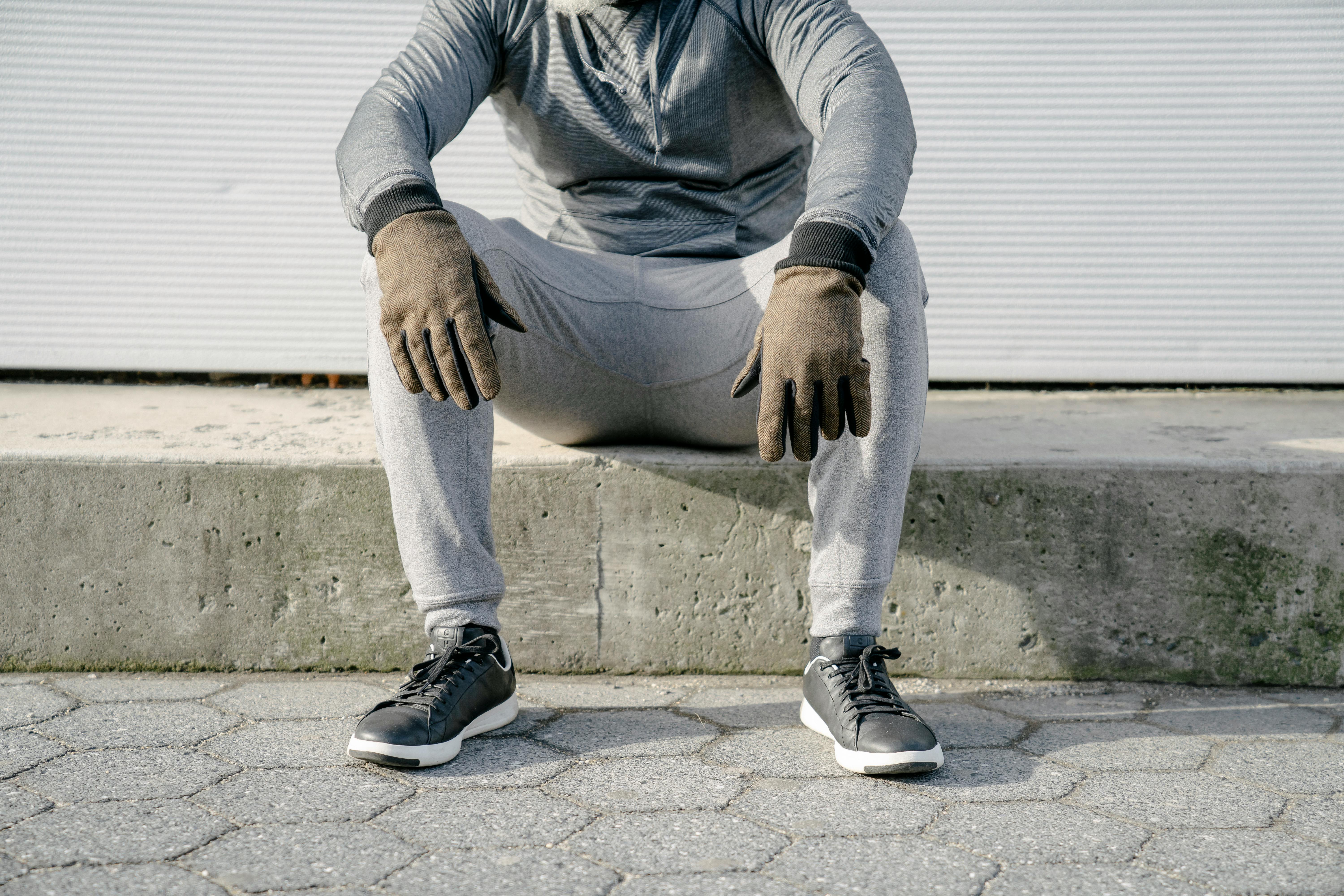 Crop faceless man in gray outfit sitting on curb · Free Stock Photo