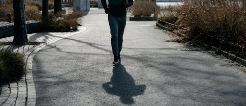 Free Crop unrecognizable man walking on road in park Stock Photo