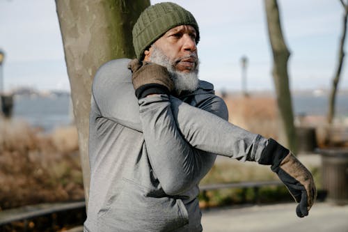 Concentrated mature black man doing side arm stretch