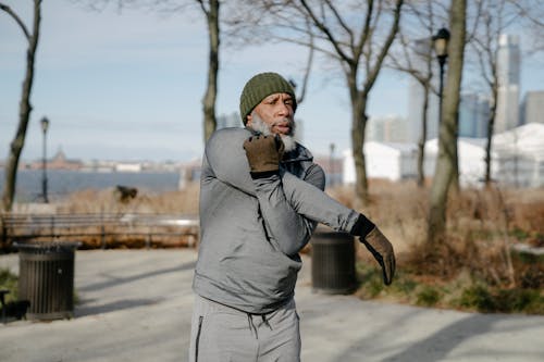 Free Senior black man stretching arm while doing morning exercise outdoors Stock Photo