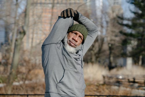 Senior black male doing exercise in park in fall