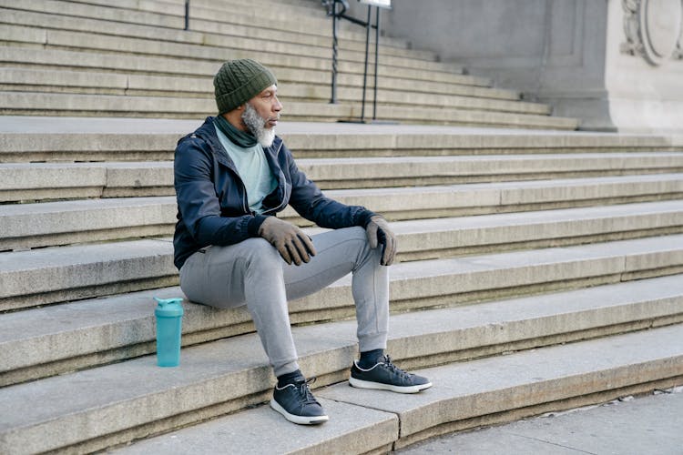 Senior Black Man In Sportswear Sitting On Stairs