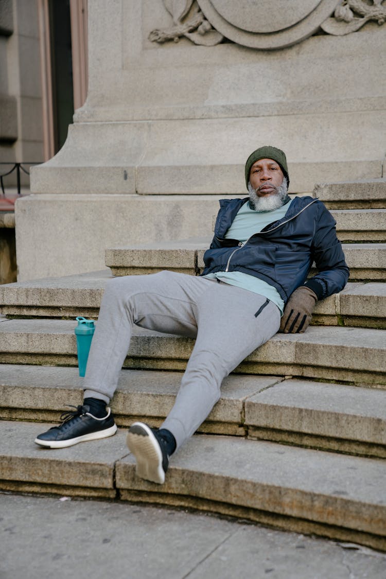 Bearded Black Man Resting On Steps Of Staircase Historic Building