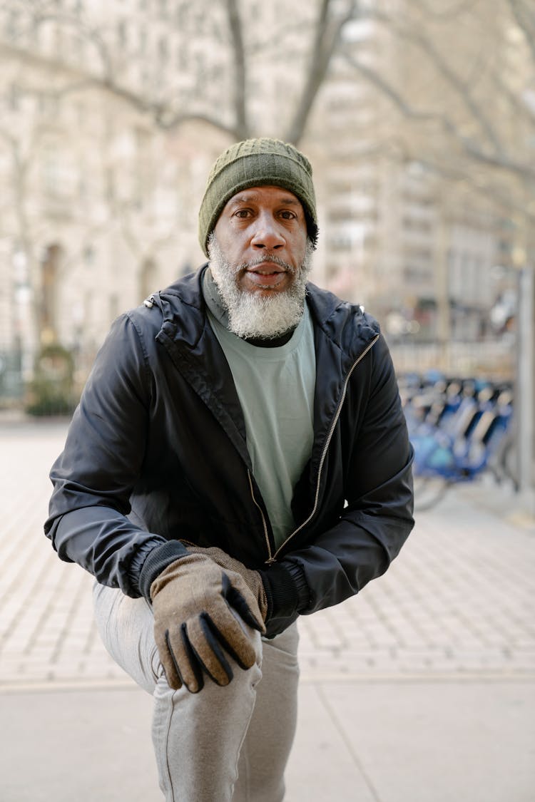 Serious Bearded Black Man Stretching Legs Outdoors