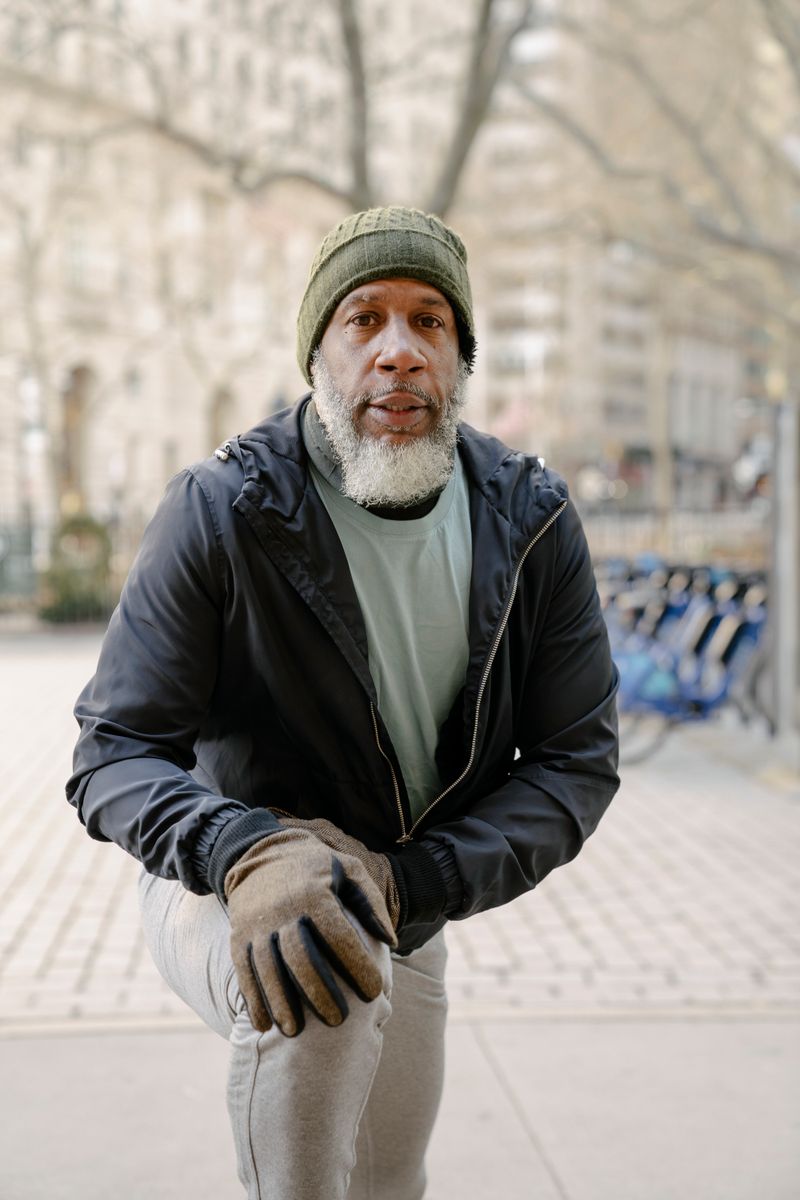 A senior Black man stretches outdoors before a morning workout.