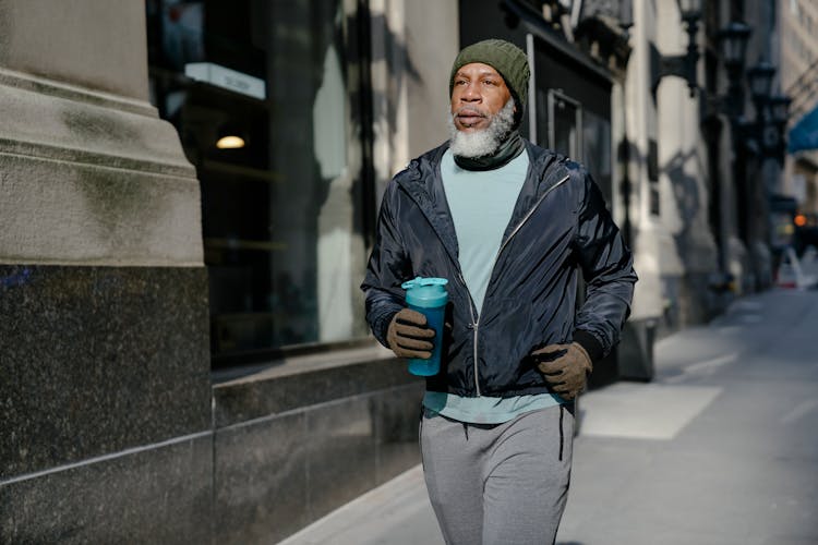 Black Man In Sportswear Jogging Near Buildings