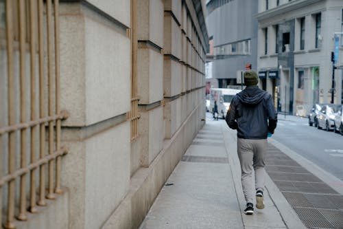 Unrecognizable man running on sidewalk in city