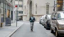 African American man with fitness bottle walking along parked cars