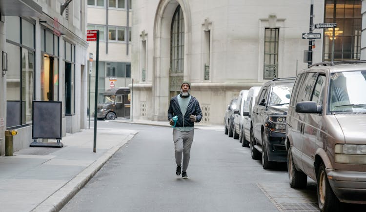 African American Man With Fitness Bottle Walking Along Parked Cars