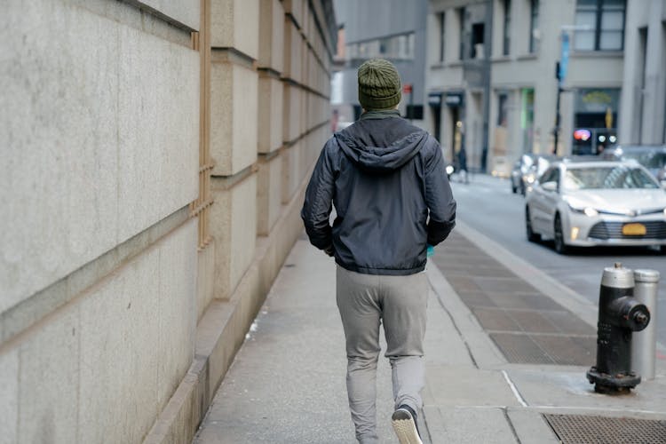 Unrecognizable Man Jogging On Sidewalk In Daytime