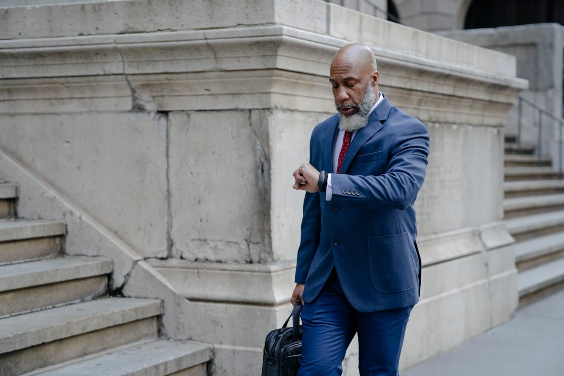 Serious black man in formal suit looking at wristwatch