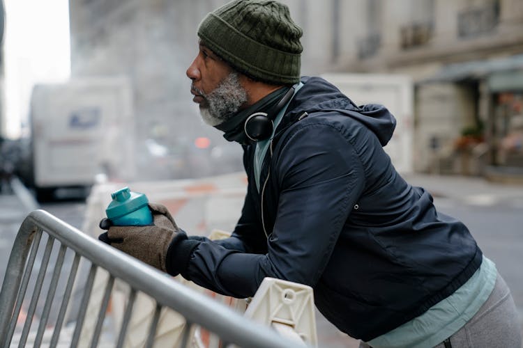 Black Man With Sport Bottle Leaning On Protective Fence