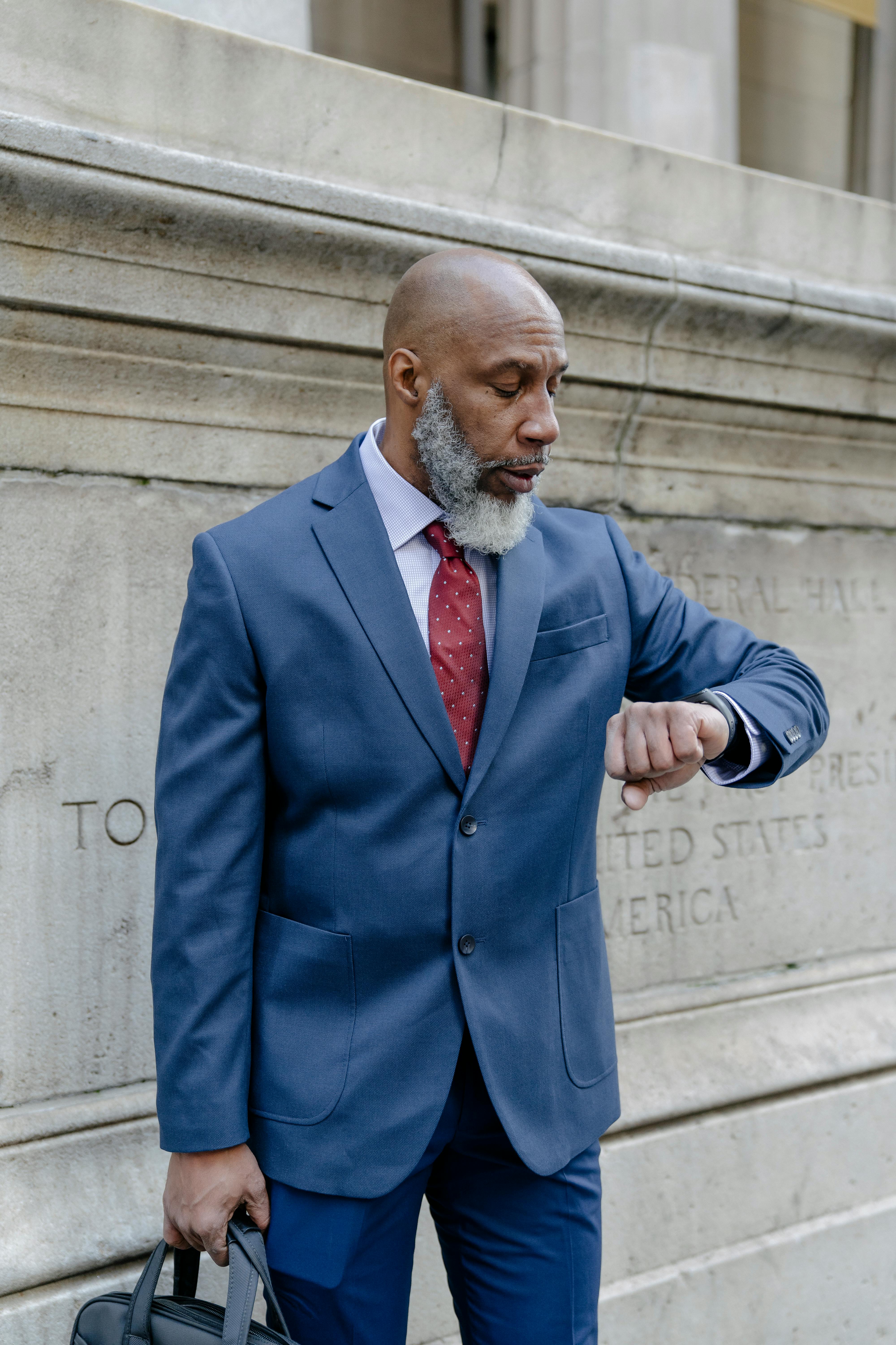 confident bearded black man in classy suit checking time on wristwatch