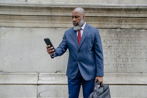 Free Man in Blue Suit Looking at His Cellphone Stock Photo