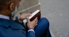 Person in Blue Long Sleeve Shirt and Blue Pants Reading Book