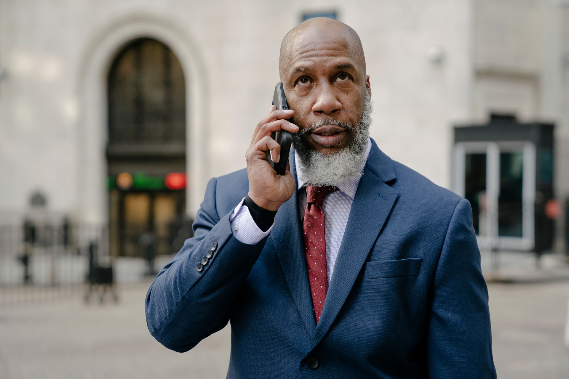 Mature businessman in a suit using a smartphone while standing outdoors.