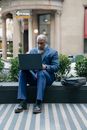 Man in Blue Sitting on a Plant Box