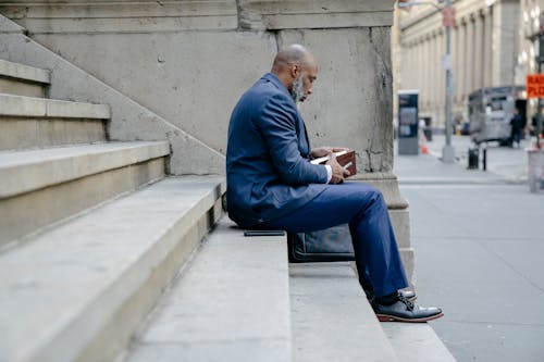 Man Holding a Notebook Sitting at the Stairs