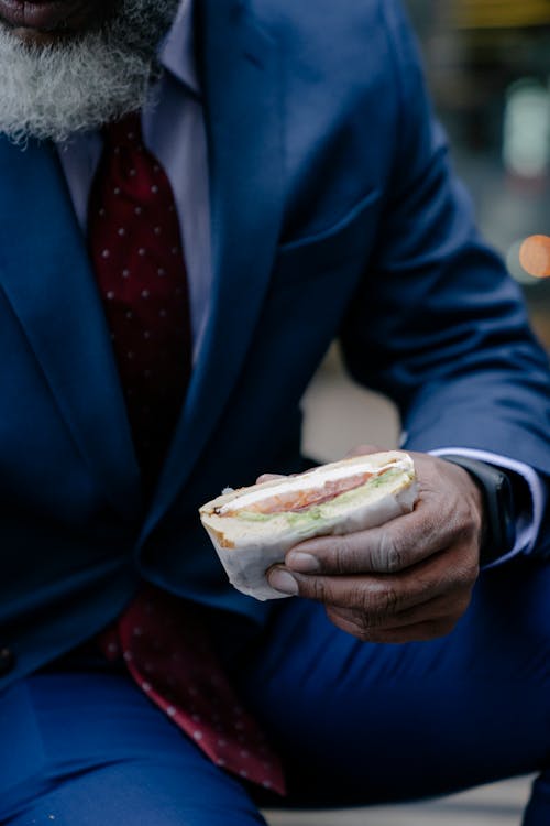 A Man in a Suit Holding a Sandwich
