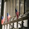 American flags hang from the grand classical columns of a major financial institution on Wall Street.