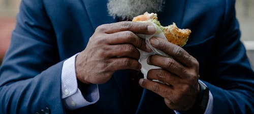 Free A Person in a Suit Holding a Sandwich Stock Photo