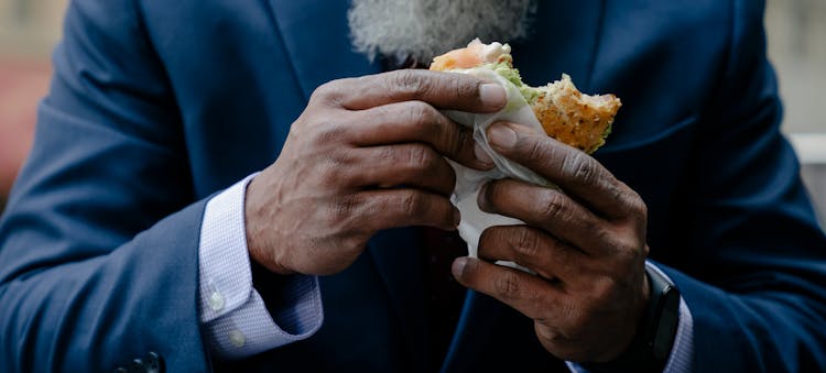 A Person In A Suit Holding A Sandwich