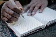 Person Writing on a Notebook