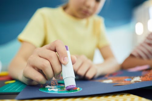 Girl Hand Holding Glue over Paper