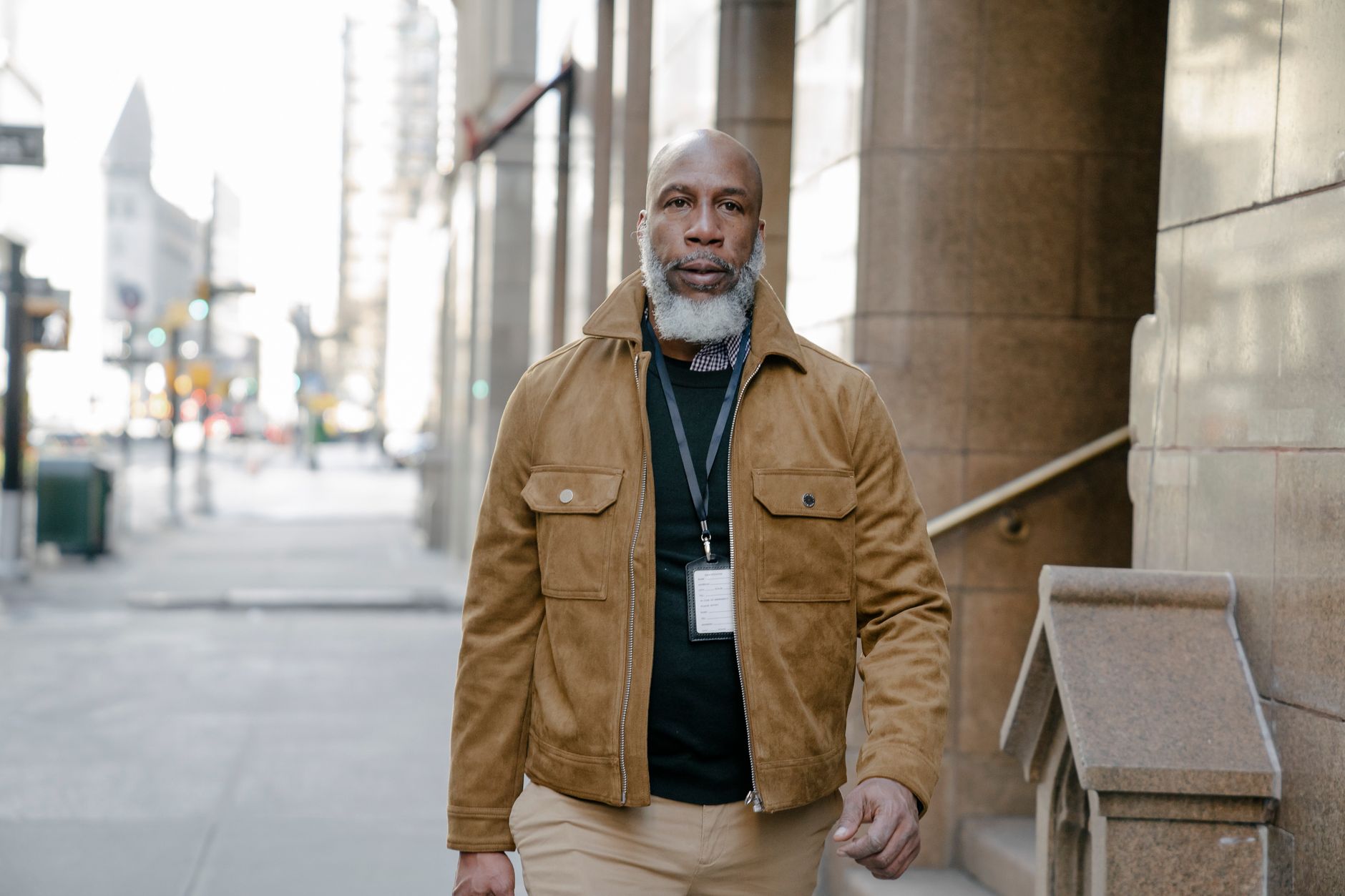 Confident man in a jacket walking through a city street