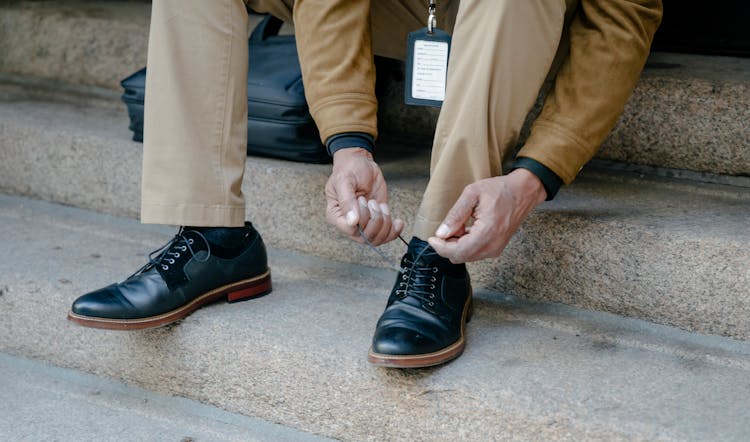 A Person Tying Their Shoes On The Stairs