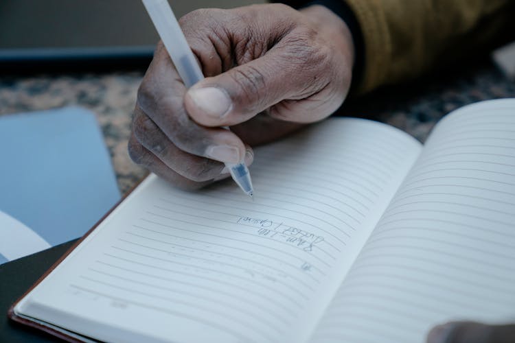 Close Up Of A Man Writing In A Notebook