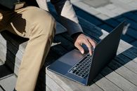 Person in Blue Long Sleeve Shirt and Brown Pants Using Macbook Pro