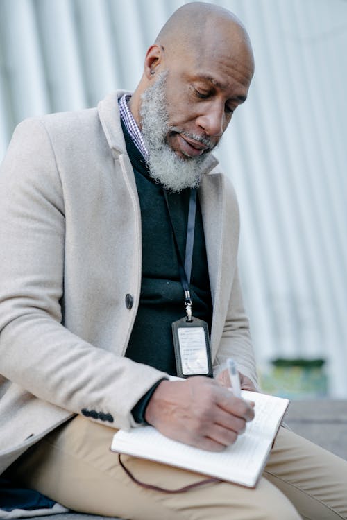 A Man Writing on Notebook using a Pen