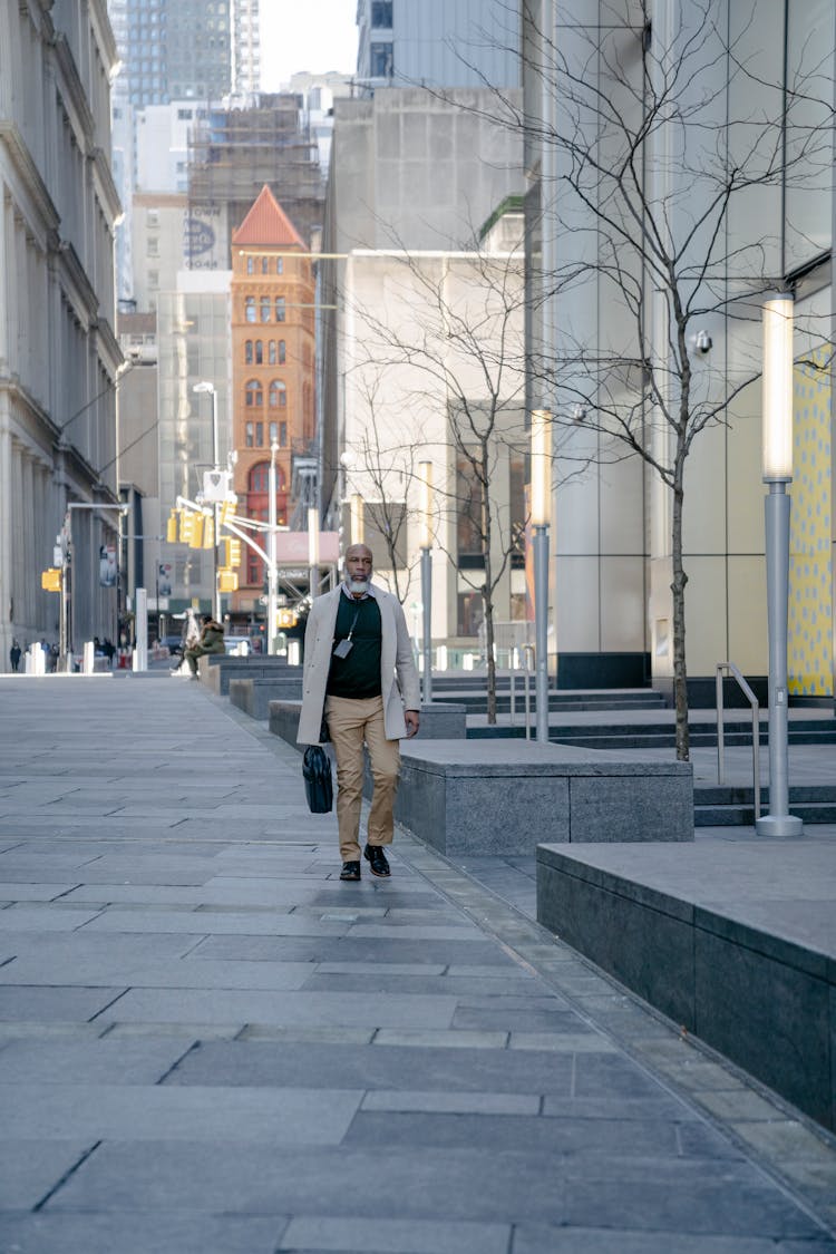 A Bald Man Walking On A Sidewalk