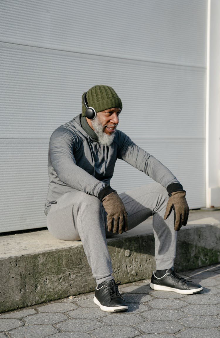 A Man In Activewear Sitting On A Curb