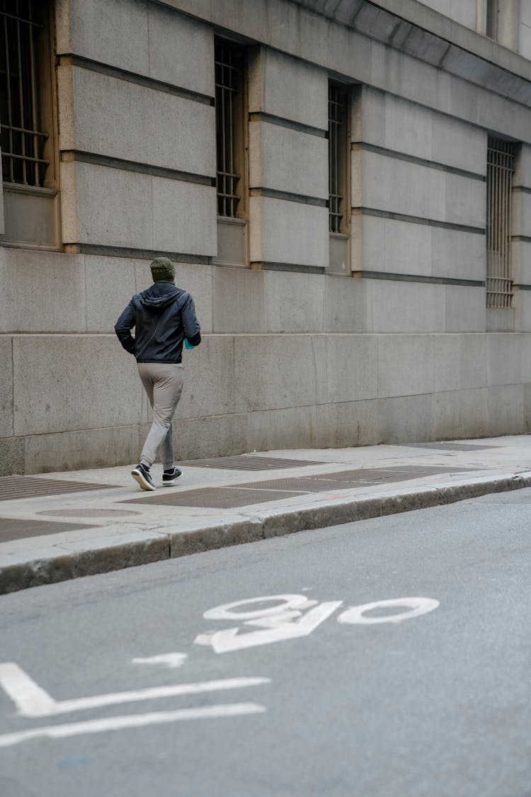 A Man Running On A Sidewalk