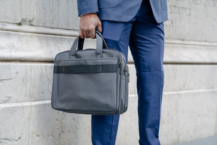 A Person In A Suit Holding A Briefcase