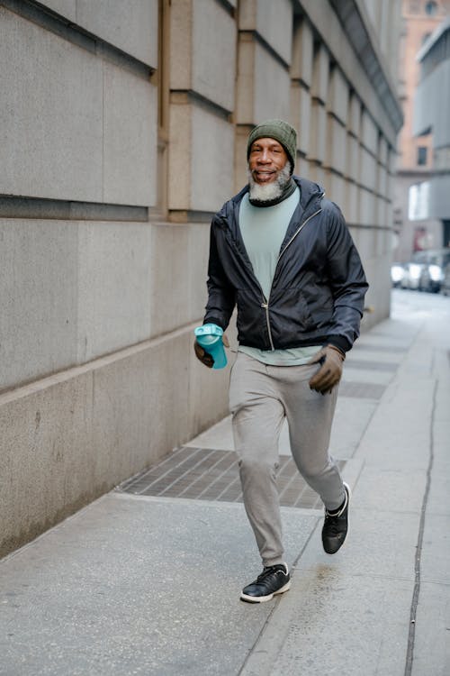 Free Man in Black Jacket Running on a Sidewalk Stock Photo
