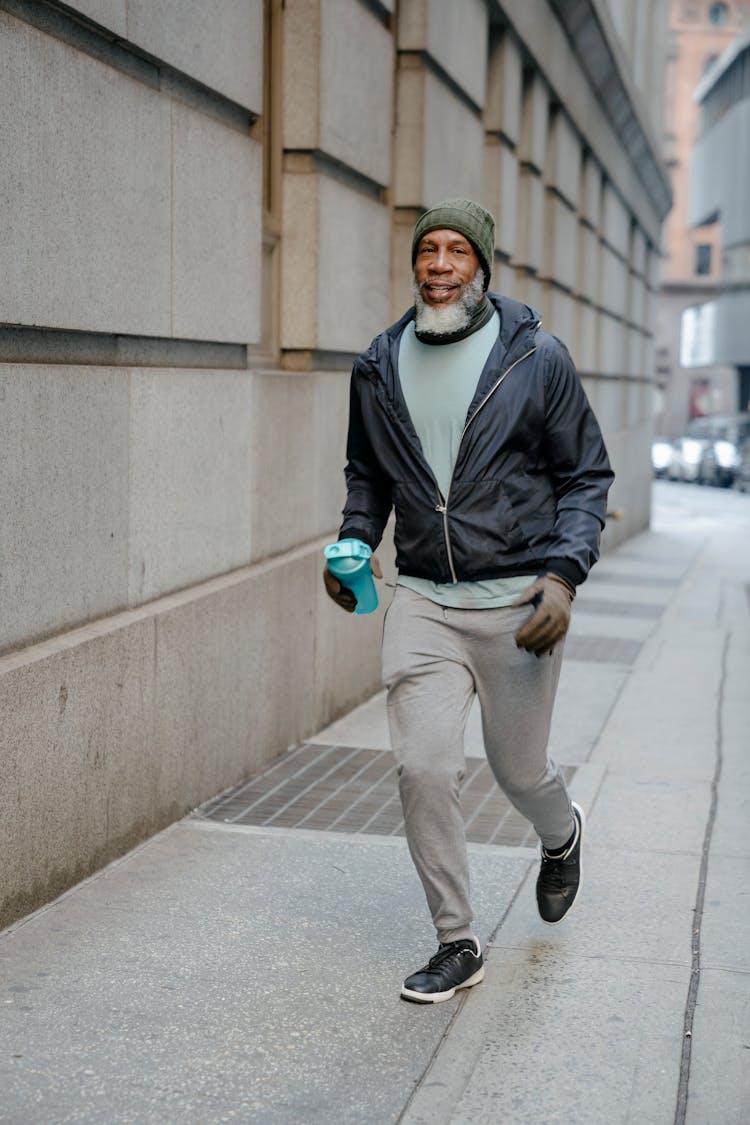 Man In Black Jacket Running On A Sidewalk