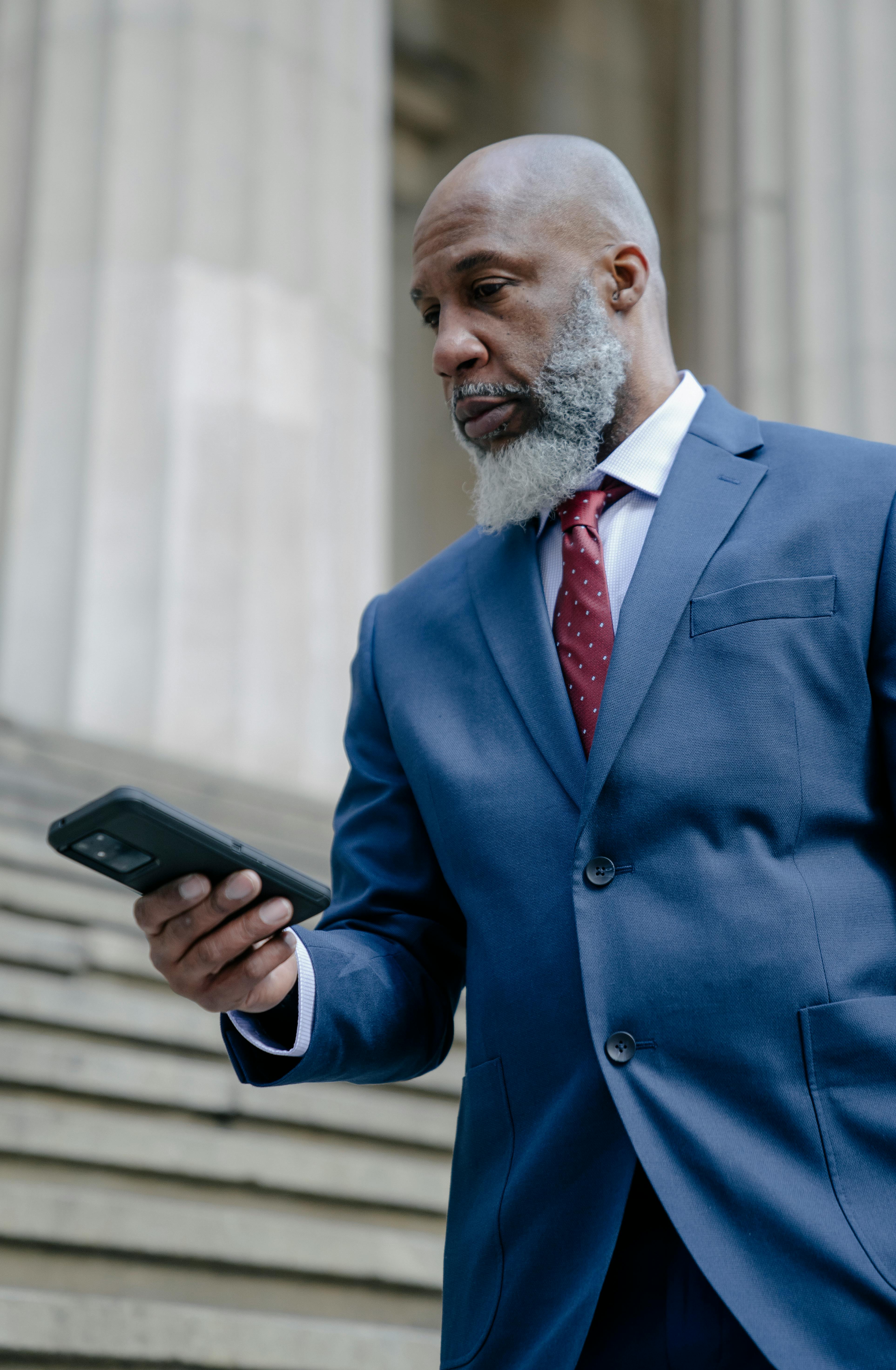 a man in blue suit holding black smartphone