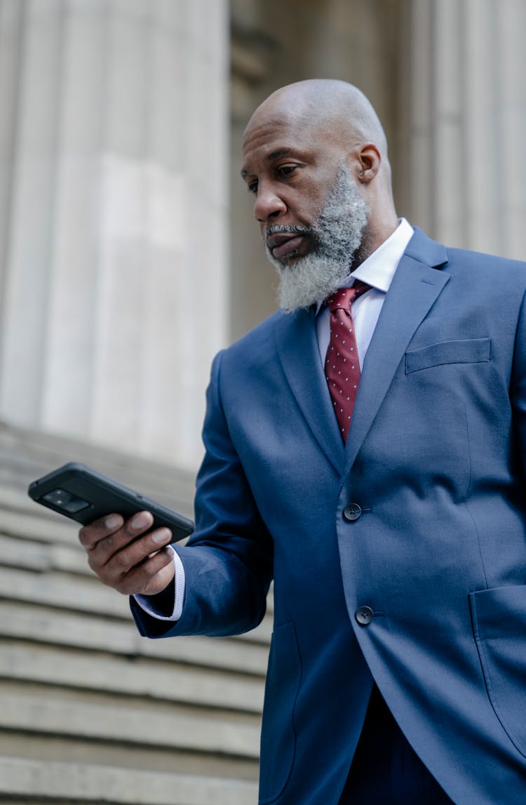 A Man In Blue Suit Holding Black Smartphone